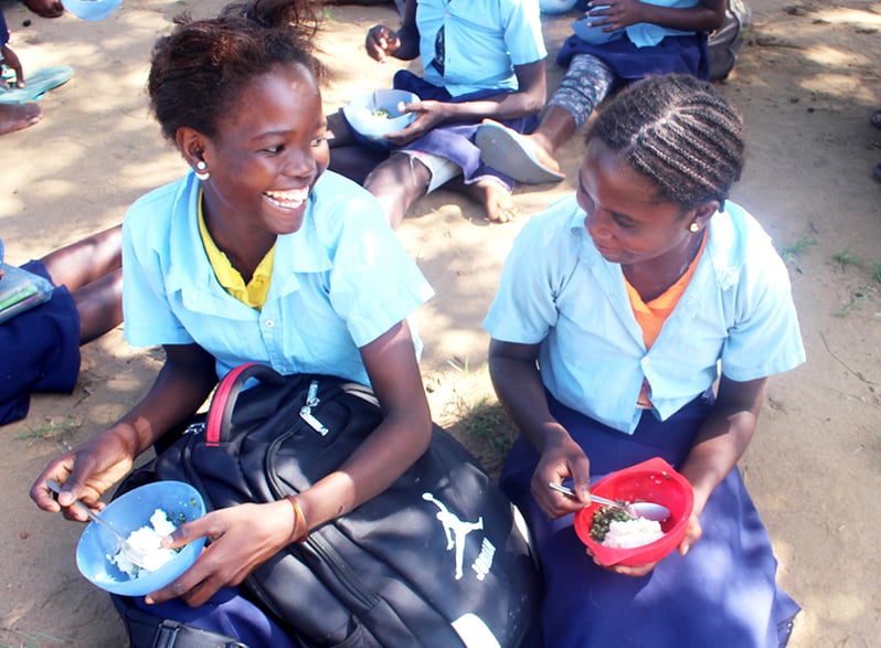 Two Mozambican primary-school girls enjoy a lunch of home-grown food.