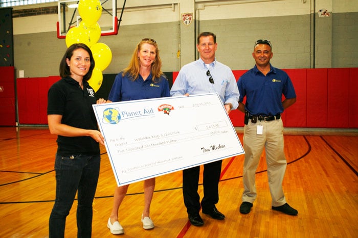 planet aid staff present donation check