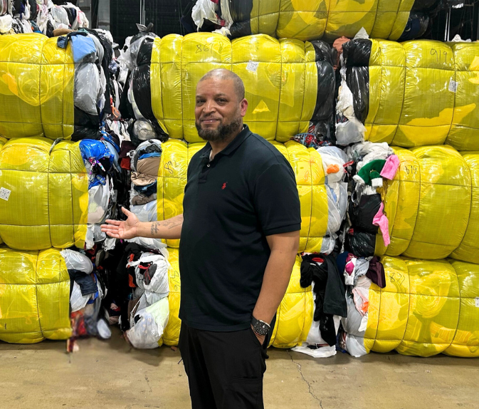 Planet Aid staff with bales of donated clothes and shoes